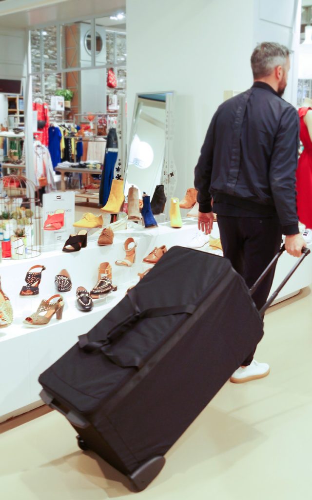 agent commercial chaussures tirant sa valise de présentation PRO G. dans un magasin de chaussures